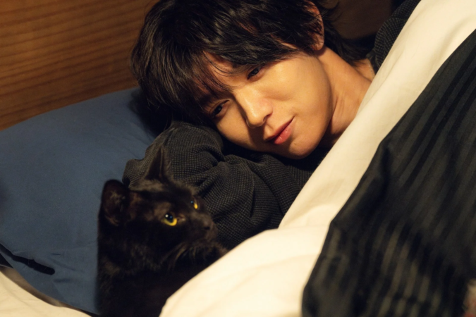 男性と黒猫がベッドでくつろぐ