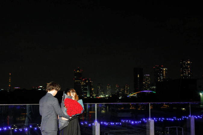 バラの花束を抱えるカップルと夜景