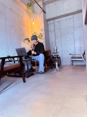 一人でシーシャとPC作業をする男性