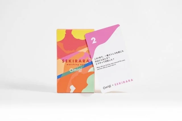 マッチングアプリ「Omiai」と「SEKIRARA」がコラボレーションした、自己開示を促す会話カードゲームのパッケージと質問カードが写っています。