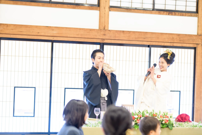ほら貝を吹く新郎と新婦