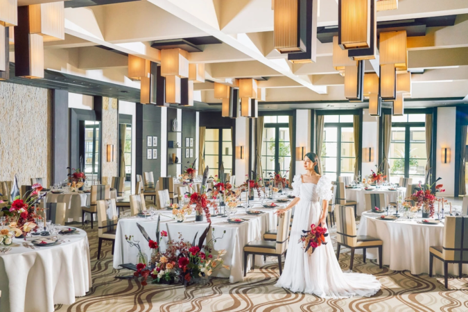 白いウェディングドレスをまとった花嫁が立つ豪華な宴会場