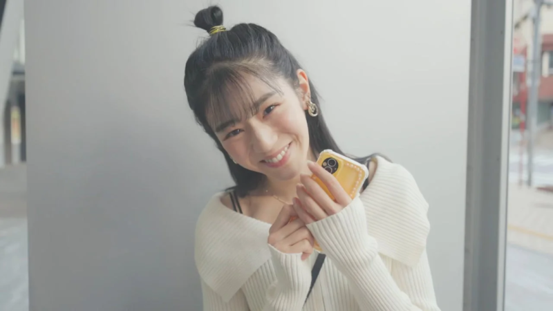 笑顔で黄色いスマートフォンを持っている若い女性