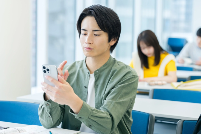 教室でスマートフォンを操作する男性