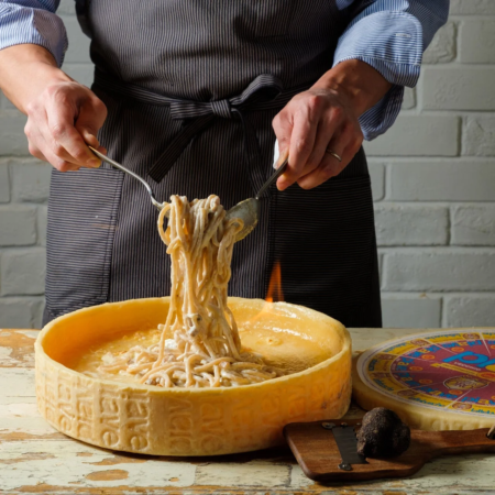 シェフが大きなチーズホイールの中でパスタを絡めている様子