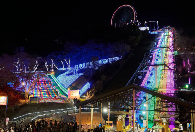 夜の遊園地でイルミネーションを楽しむ人々