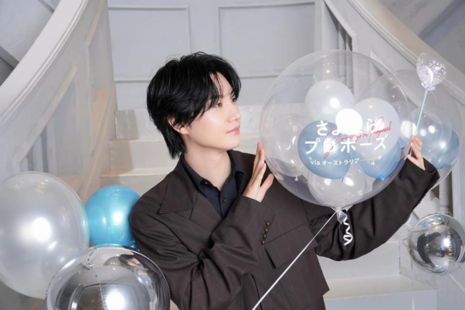 「さよならプロポーズ via オーストラリア」と書かれた透明なバルーンを持つ若い男性