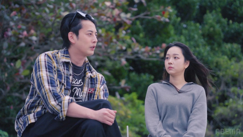 屋外で向かい合って座る石黒英雄さんと池田陽花さん