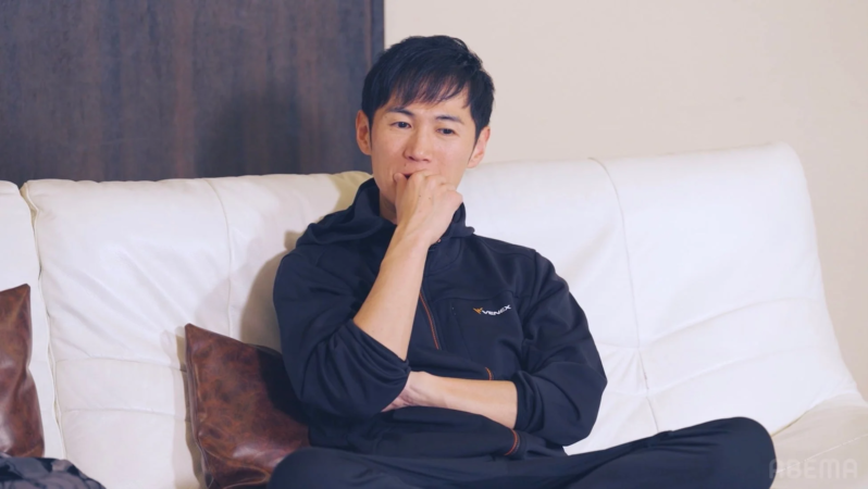 ソファに座り、口元に手を当てて考え込んでいる男性