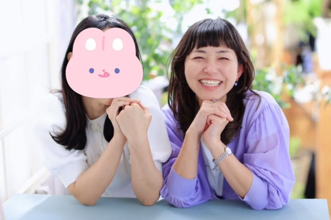 テーブルで笑顔の女性と顔が隠された女性