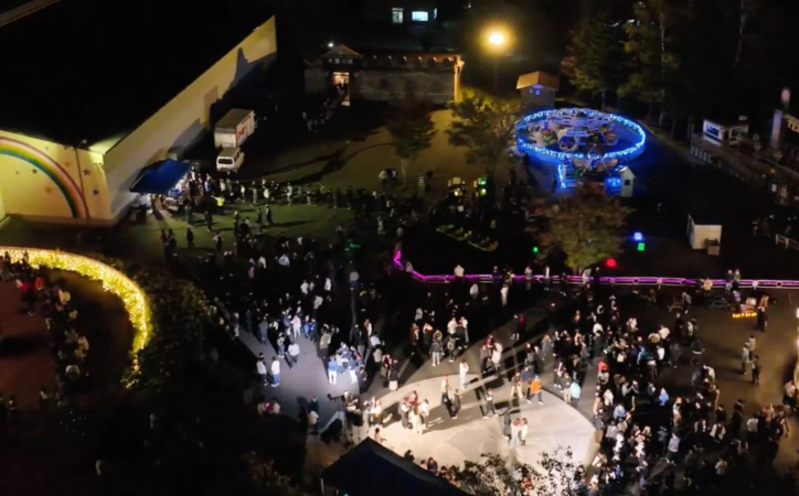 夜の遊園地でイルミネーションを楽しむ人々