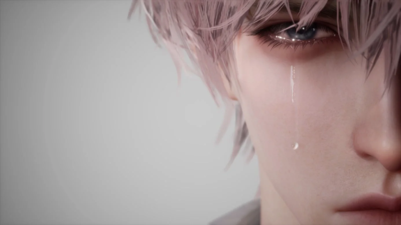 青い目から一筋の涙を流す、ピンク色の髪の男性の顔のクローズアップ画像です。