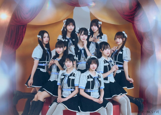 赤いカーテンを背景にポーズをとる9人の女性アイドルグループ