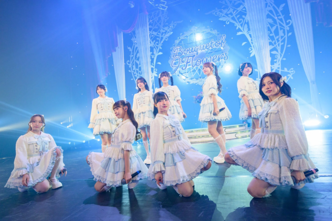 青い照明が当たるステージでパフォーマンスするアイドルグループ