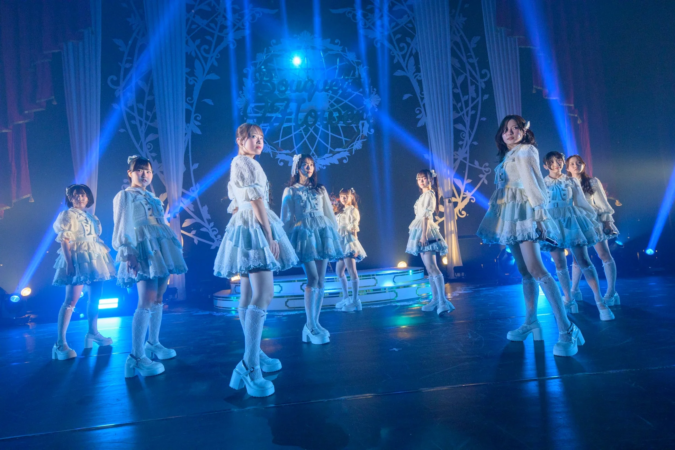 青い照明が印象的なステージでパフォーマンスするアイドルグループ