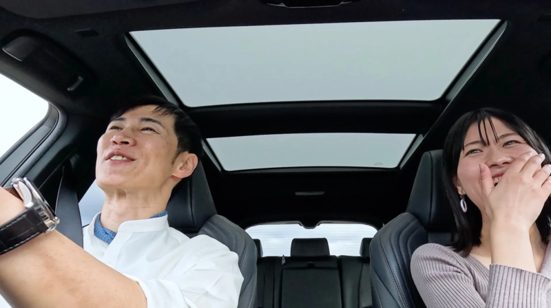 車内で笑顔を見せる石丸伸二といずみ