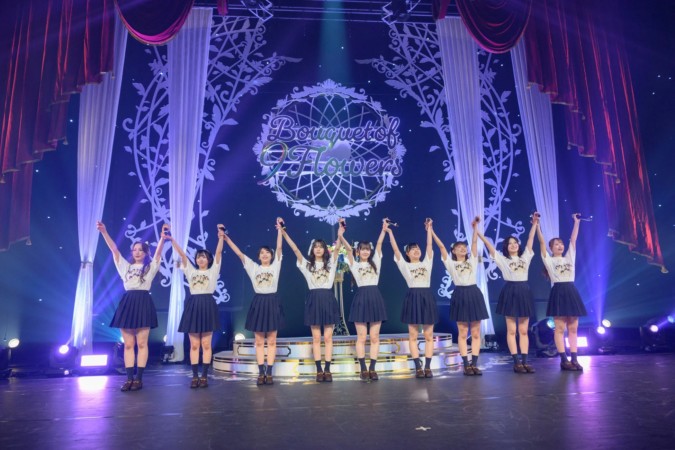 ステージ上でパフォーマンスを締めくくる9人の女性アイドルグループ