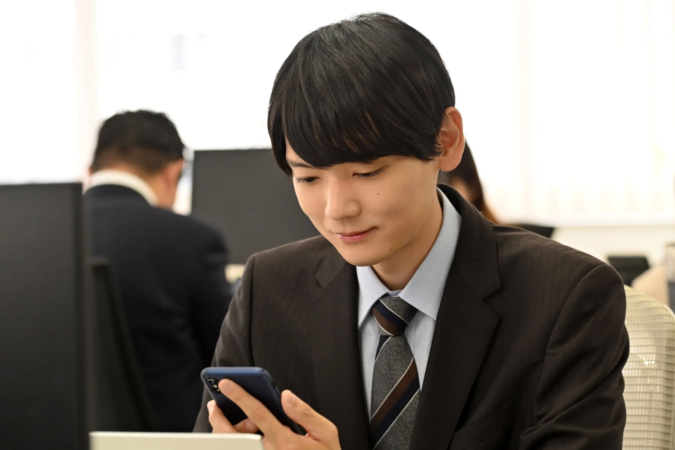 オフィスでスマートフォンを操作する慶伊
