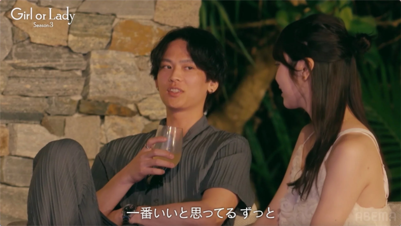 夜の屋外で、若い男女がリラックスした雰囲気で会話している様子