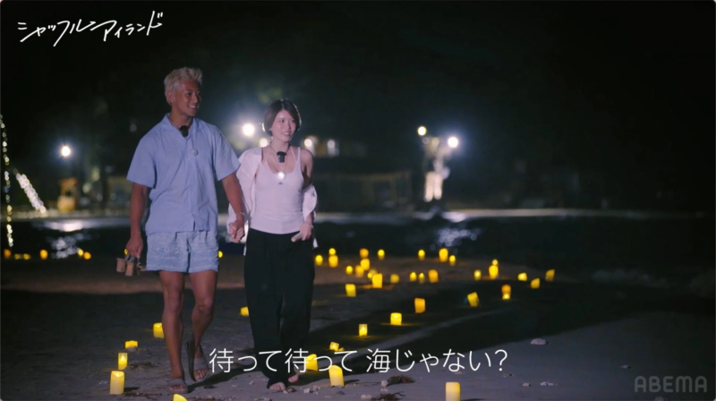夜のビーチを歩くカップル