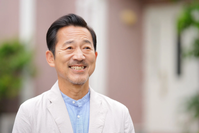 屋外で笑顔を見せる中年男性