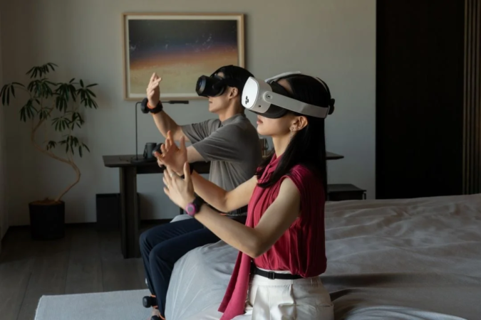 男女がVRヘッドセットを装着し、仮想空間でジェスチャーを使って何かを操作している様子